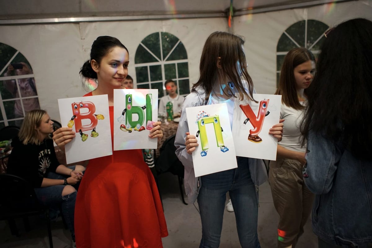 Ведущая и выпускники с буквами в шатре